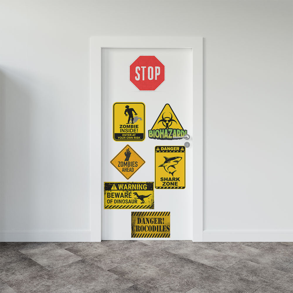 A white door in a room setting decorated with various humorous and spooky warning signs, including a red stop sign, a zombie intrusion sign, a biohazard sign, a dinosaur warning sign, and a shark zone sign.