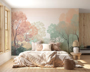 Elegant woodland wall mural and wallpaper featuring soft autumn forest hues with trees in peach, green and beige, styled in a cozy bedroom with a neutral palette.
