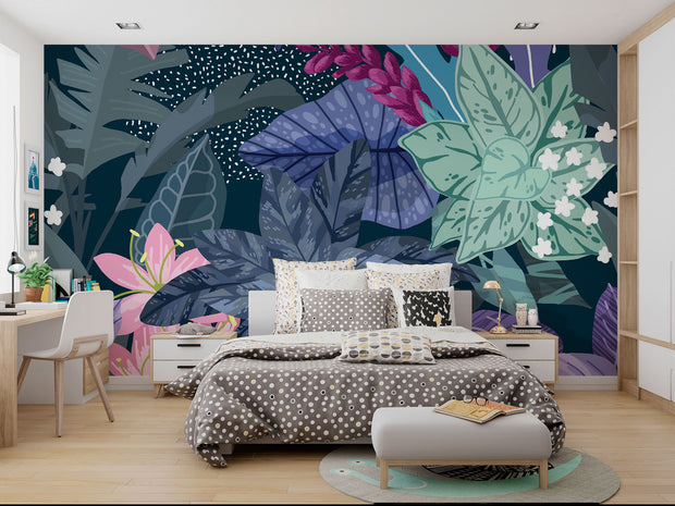 Illustrated tropical botanical wall mural with large jungle leaves, pink lilies, white flowers, and deep blue background, styled in a modern bedroom.