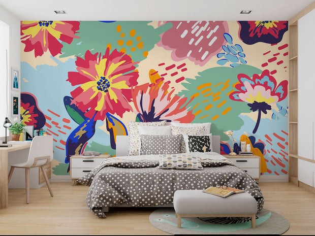 Vibrant floral wall mural with bold, hand-painted flowers in red, yellow, blue, and green, displayed in a modern bedroom setting.