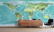 High-detail oversized world map wall mural showing terrain relief and ocean depths in turquoise and green, styled with modern furniture.