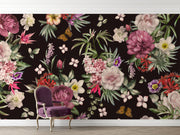 Moody flower wallpaper with dark background and large pink peonies behind a purple velvet chair.