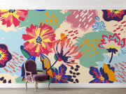 Vibrant floral wall mural with bold, hand-painted flowers in red, yellow, blue, and green, displayed in a  living room setting.
