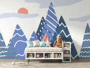Adventure Peaks wall mural featuring abstract mountain shapes in blue and peach tones with a sun and clouds, styled in a boy’s bedroom.