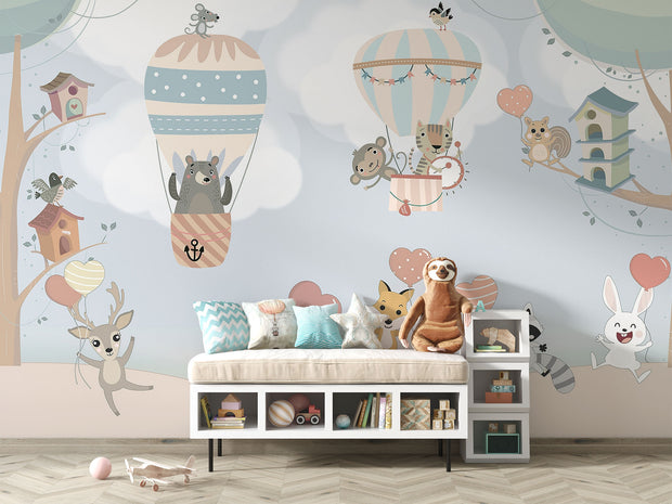 Nursery wall mural with pastel-colored forest animals flying in hot air balloons, surrounded by trees, clouds, and heart-shaped balloons