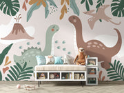 Kids’ wall mural with cartoon dinosaurs, volcano, pterodactyl, and tropical leaves in soft earth tones; styled in a cozy children’s playroom.