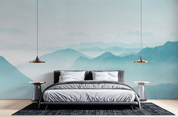 Serene misty mountain wall mural with soft blue gradient layers, creating a peaceful atmosphere in a modern bedroom setting.