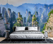 Zhangjiajie Mountain landscape wall mural featuring sandstone pillars, lush greenery, and misty peaks in a modern bedroom.