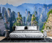 Zhangjiajie Mountain landscape wall mural featuring sandstone pillars, lush greenery, and misty peaks in a modern bedroom.