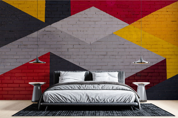 Modern geometric wall mural with an urban brick texture featuring bold abstract shapes in red, yellow, black, and gray. Ideal for industrial-style living rooms, lofts, and offices.