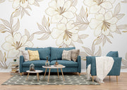 Elegant gold floral wall mural with oversized flowers and intricate leaves, featured in a modern living room with blue sofa.