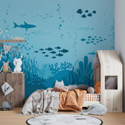 Underwater-themed wall mural featuring silhouettes of sharks, fish, and coral reefs in varying shades of blue, perfect for a calming and playful kids’ room.
