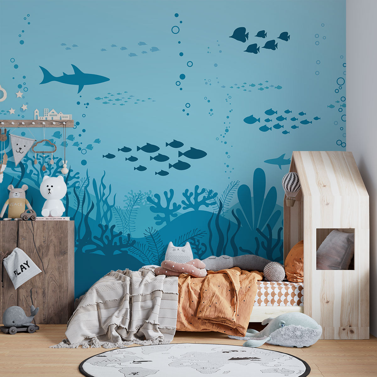 Underwater-themed wall mural featuring silhouettes of sharks, fish, and coral reefs in varying shades of blue, perfect for a calming and playful kids’ room.
