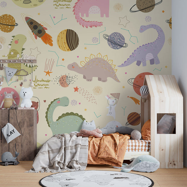 Children's room with Dino Galaxy Wall Mural featuring whimsical dinosaurs, rockets, planets, and stars in pastel colors, creating a magical space-themed decor.
