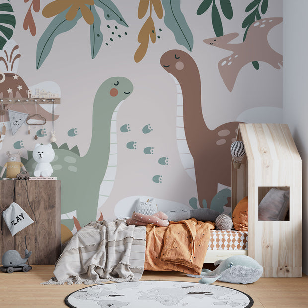 Kids’ wall mural with cartoon dinosaurs, volcano, pterodactyl, and tropical leaves in soft earth tones; styled in a cozy children’s bedroom.