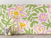Floral wall mural with bold pink and yellow flowers and green leaves, decorating a nursery.