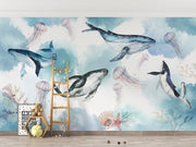 Underwater ocean wall mural with watercolor whales, jellyfish, and coral reefs in calming blue tones, displayed in a children's room with cozy decor.
