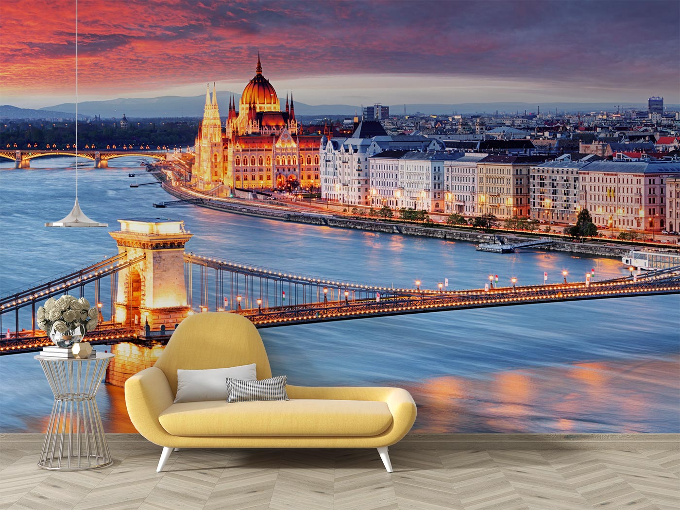 Budapest Skyline Wall Mural featuring the Hungarian Parliament, Chain Bridge, and the Danube River glowing under a vibrant sunset; decorating a living room with yellow sofa.