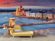 Budapest Skyline Wall Mural featuring the Hungarian Parliament, Chain Bridge, and the Danube River glowing under a vibrant sunset; decorating a living room with yellow sofa.