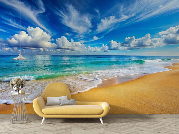 Serene beach wall mural featuring turquoise ocean waves, golden sand and a blue sky with fluffy clouds, decorating a living room.