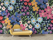 Colorful floral wall mural with hand-painted flowers in shades of blue, pink, yellow, and purple, displayed in a modern living room with a pastel sofa.