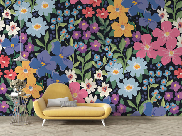 Colorful floral wall mural with hand-painted flowers in shades of blue, pink, yellow, and purple, displayed in a modern living room with a pastel sofa.