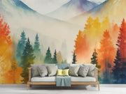 Watercolor mountain landscape wall mural with autumn forest in orange, yellow and teal, styled in modern living room.