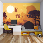 Kids’ dinosaur wall mural featuring silhouettes of Brachiosaurus, Pterosaurs, and prehistoric trees against an orange sunset, ideal for a playful bedroom or playroom.