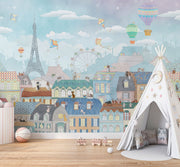 Paris-themed kids’ wall mural with the Eiffel Tower, hot air balloons, colorful rooftops, and kites in soft pastel colors, perfect for a nursery or playroom.