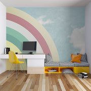 Modern bedroom with retro pastel rainbow wall mural and sky backdrop, styled with minimalist white furniture.