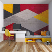 Modern geometric wall mural with an urban brick texture featuring bold abstract shapes in red, yellow, black, and gray. Ideal for industrial-style living rooms, lofts, and offices.
