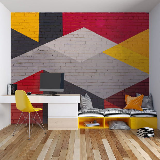 Modern geometric wall mural with an urban brick texture featuring bold abstract shapes in red, yellow, black, and gray. Ideal for industrial-style living rooms, lofts, and offices.