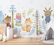 Winter woodland animal wall mural featuring a bear, fox, deer, and owl in cozy knitted sweaters, surrounded by snow-covered trees and soft blue foliage.