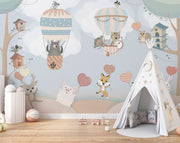 Nursery wall mural with pastel-colored forest animals flying in hot air balloons, surrounded by trees, clouds, and heart-shaped balloons