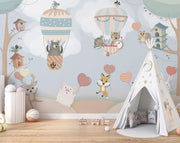 Nursery wall mural with pastel-colored forest animals flying in hot air balloons, surrounded by trees, clouds, and heart-shaped balloons