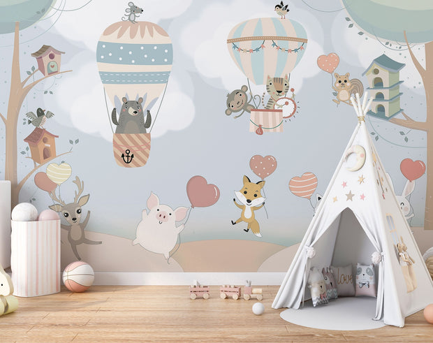 Nursery wall mural with pastel-colored forest animals flying in hot air balloons, surrounded by trees, clouds, and heart-shaped balloons