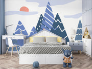 Adventure Peaks wall mural featuring abstract mountain shapes in blue and peach tones with a sun and clouds, styled in a boy’s bedroom.