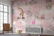 A whimsical nursery wall mural featuring playful animals, including a giraffe on a scooter, an elephant on a bike, and a panda floating with balloons over pink clouds.