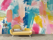 Colorful abstract wall mural with brushstroke patterns in vibrant pink, blue, yellow, and coral shades, installed in a modern living room.