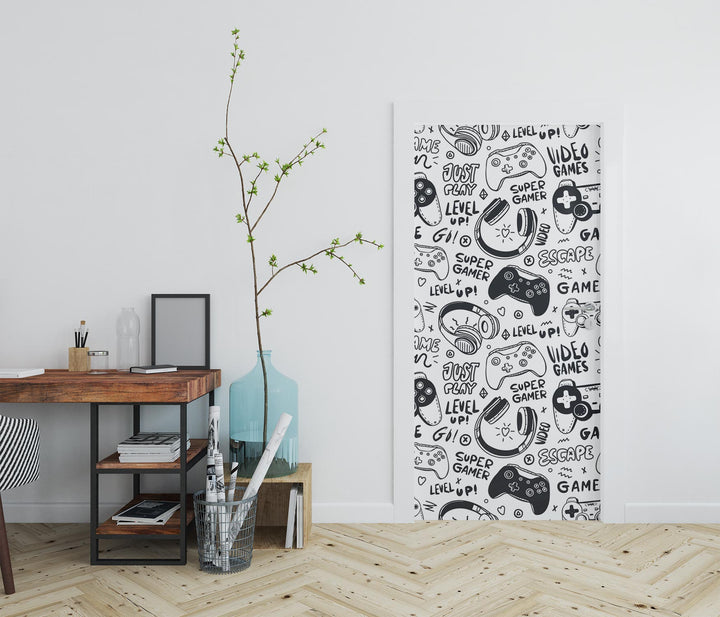 Black-and-white gaming-themed door mural featuring video game controllers, gamer doodles, and phrases like "Level Up!" and "Just Play!"