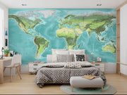 High-detail oversized world map wall mural showing terrain relief and ocean depths in turquoise and green, styled with modern furniture.