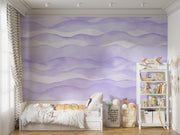 Purple wave-pattern wall mural with soft flowing designs, decorating a cosy children’s bedroom with a white bed, playful decor and a shelf filled with toys and books.