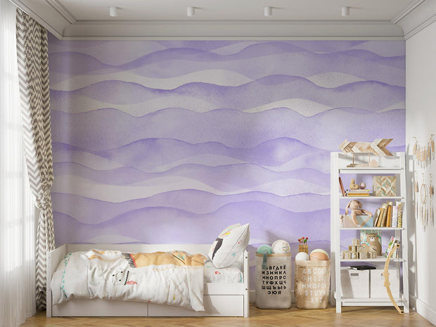 Purple wave-pattern wall mural with soft flowing designs, decorating a cosy children’s bedroom with a white bed, playful decor and a shelf filled with toys and books.