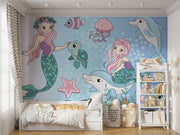Whimsical underwater-themed mural with pastel mermaids, dolphins, turtles, jellyfish, and fish set against a blue bubble-filled background in a cozy kids' room.
