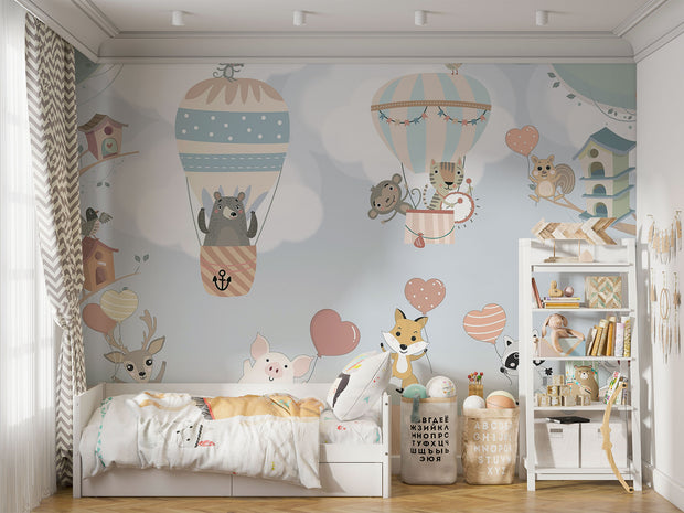 Nursery wall mural with pastel-colored forest animals flying in hot air balloons, surrounded by trees, clouds, and heart-shaped balloons