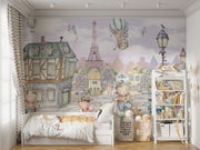 A whimsical Paris-inspired nursery wall mural featuring teddy bears on scooters and bikes, cobblestone streets, and the Eiffel Tower in pastel tones.