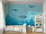Underwater-themed wall mural featuring silhouettes of sharks, fish, and coral reefs in varying shades of blue, perfect for a calming and playful kids’ room.