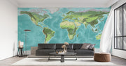 High-detail oversized world map wall mural showing terrain relief and ocean depths in turquoise and green, styled with modern furniture.
