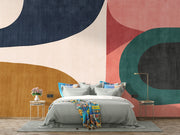 Earthy geometric wall mural with abstract curved shapes in green, ochre, navy, and blush, creating a modern and minimalist bedroom atmosphere.