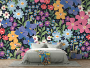 Colorful floral wall mural with hand-painted flowers in shades of blue, pink, yellow, and purple, displayed in a modern bedroom.